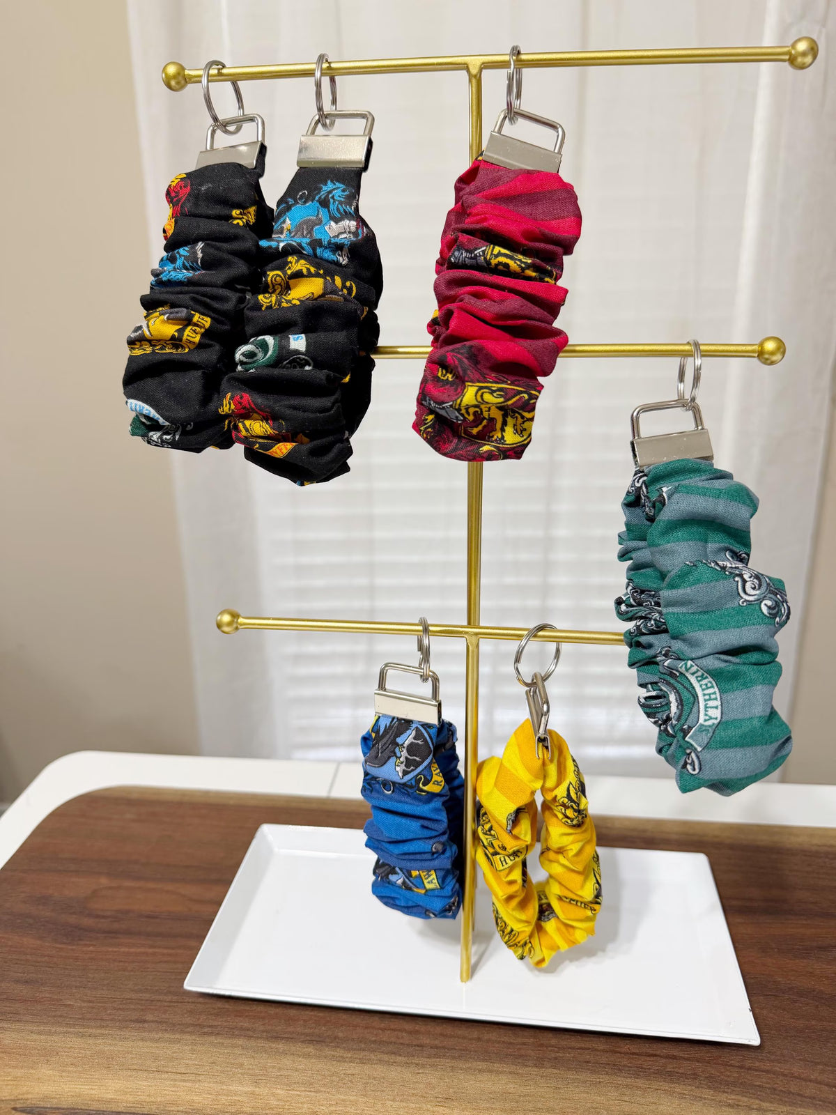 Colorful scrunchies on a gold rack against a white curtain background